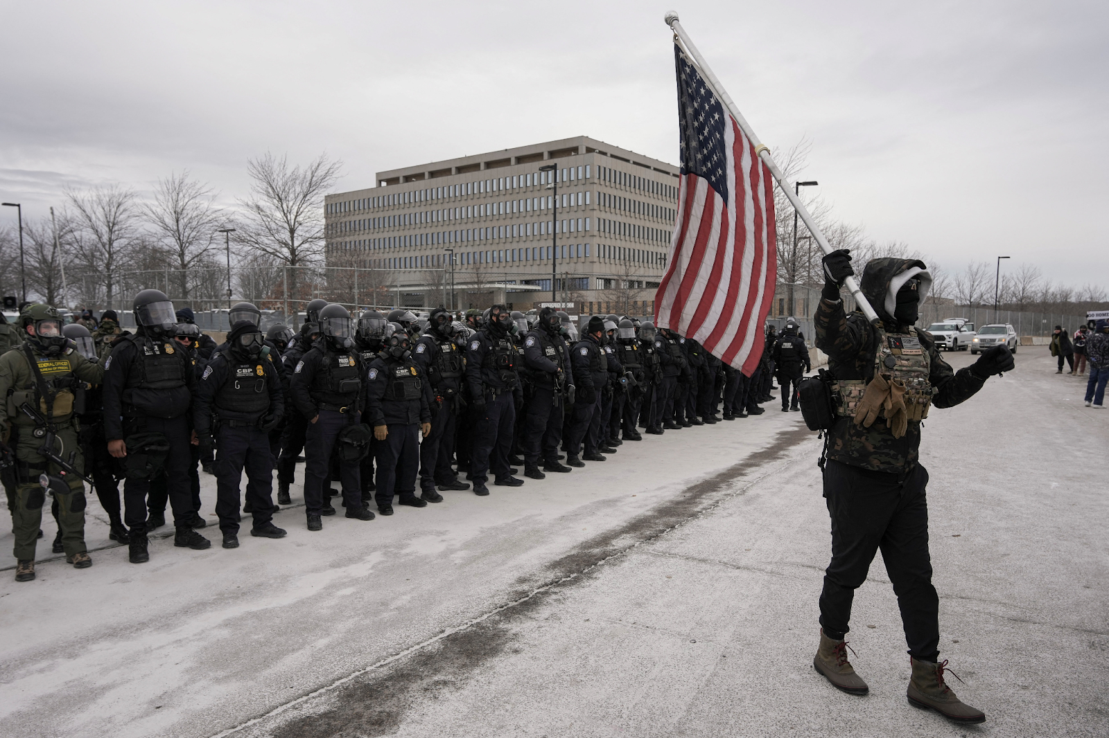 A counter-protester with a U.S. flag in front of Immigration and Customs Enforcement (ICE) agents, outside the Whipple Federal Building in Minneapolis, Minnesota | REUTERS/Tim Evans